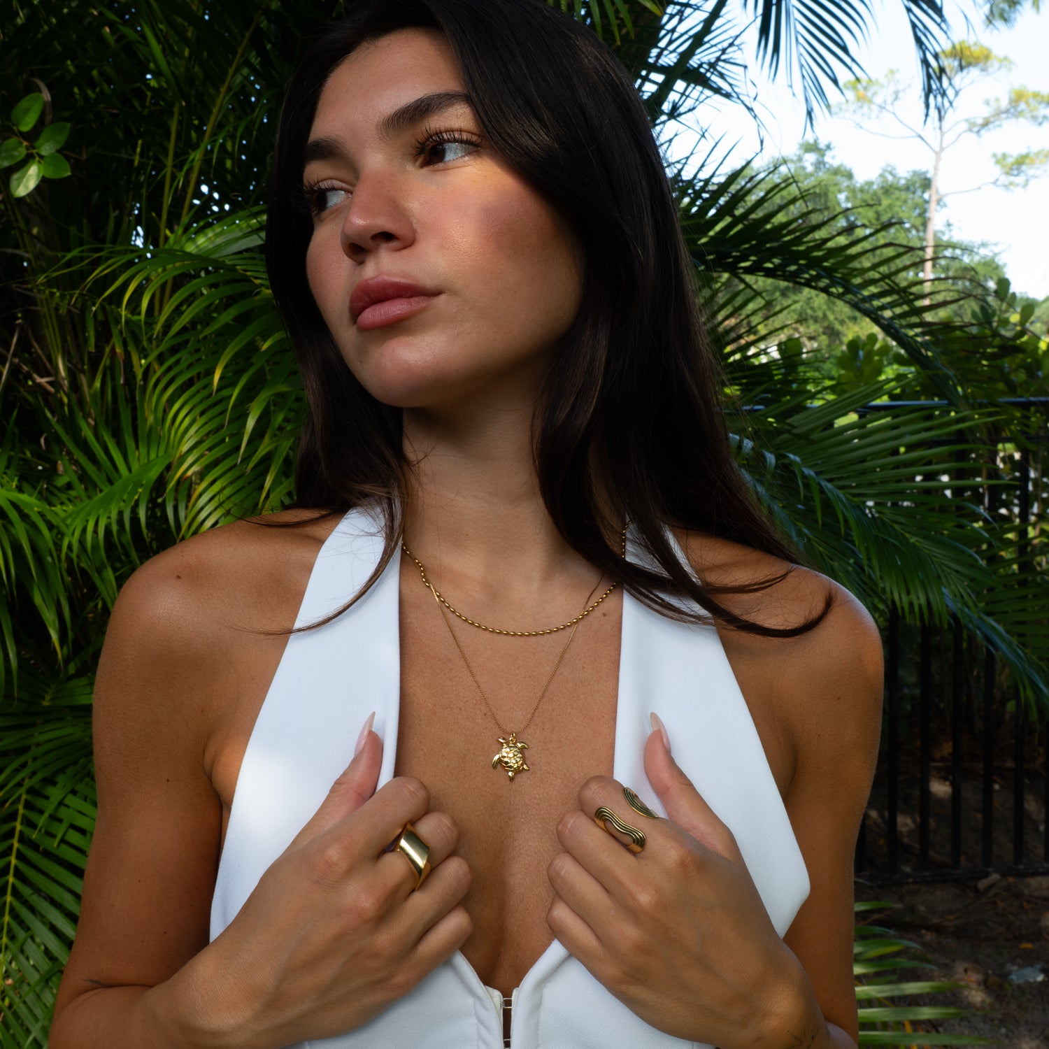 Model wearing handmade gold sea turtle talisman layered necklace outdoors