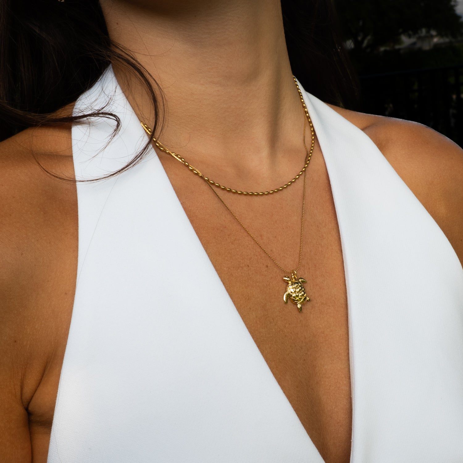 Woman wearing sacred sea turtle layered necklace with white halter top