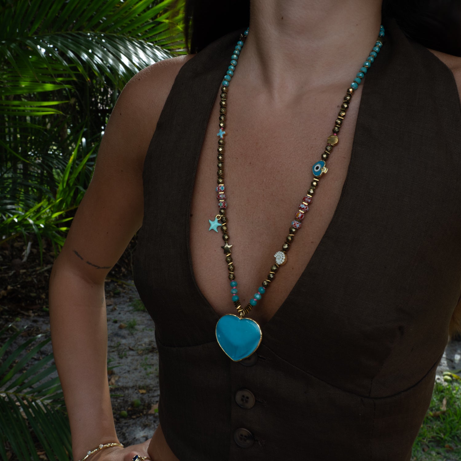 Model styling ocean blue heart beaded summer necklace with brown linen vest by Ebru Jewelry