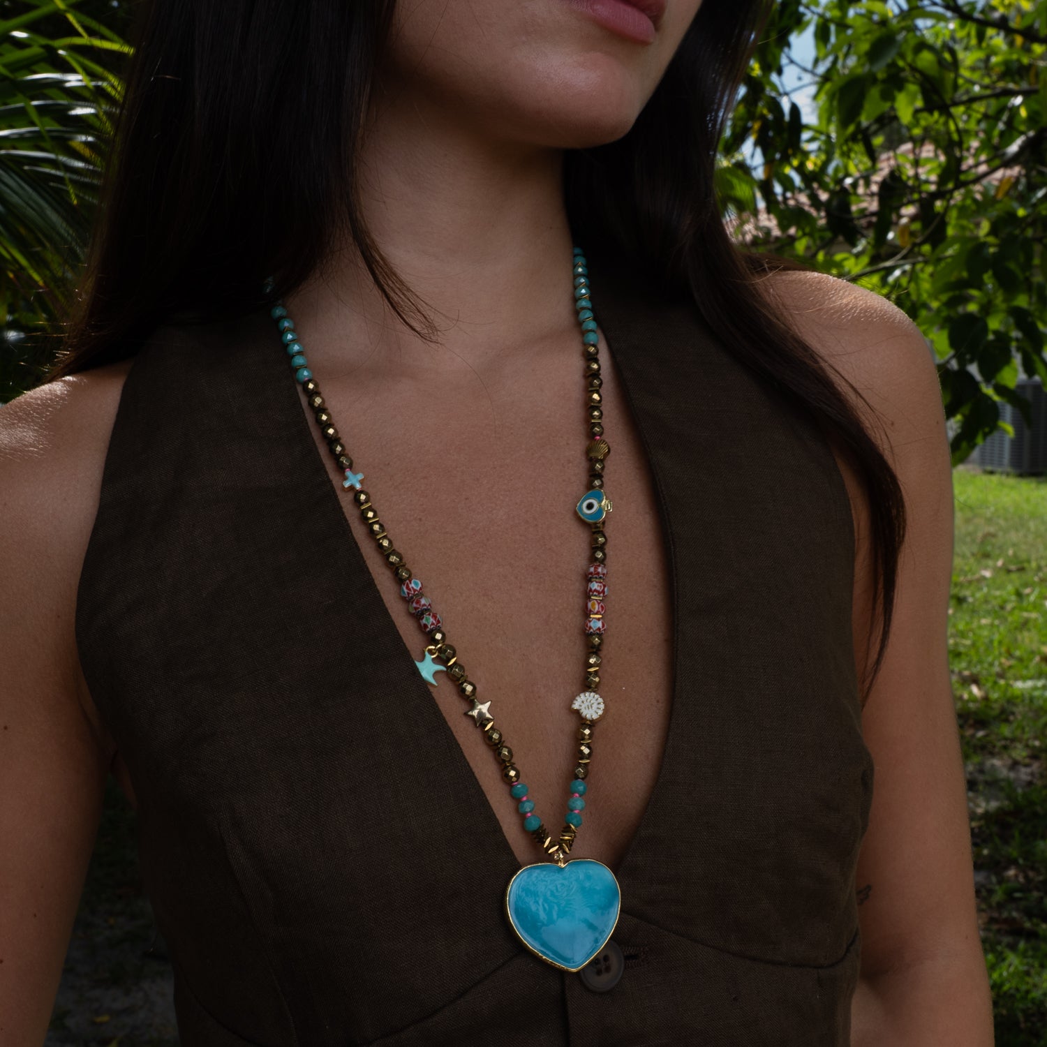 Close-up of ocean blue glass heart pendant on hand-strung beaded summer necklace