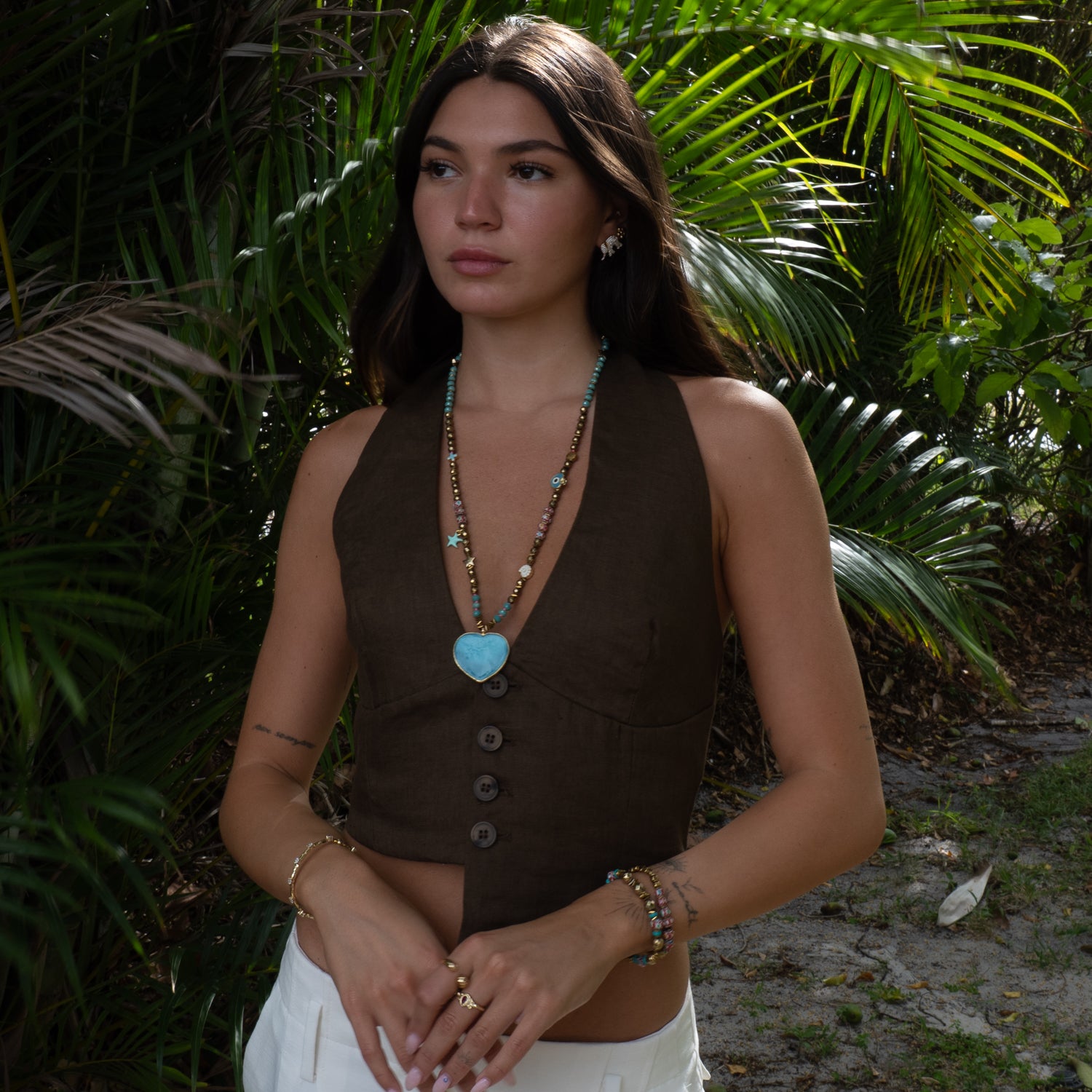 Model wearing Salt & Sun Heart beaded summer necklace with blue glass heart, layered styling