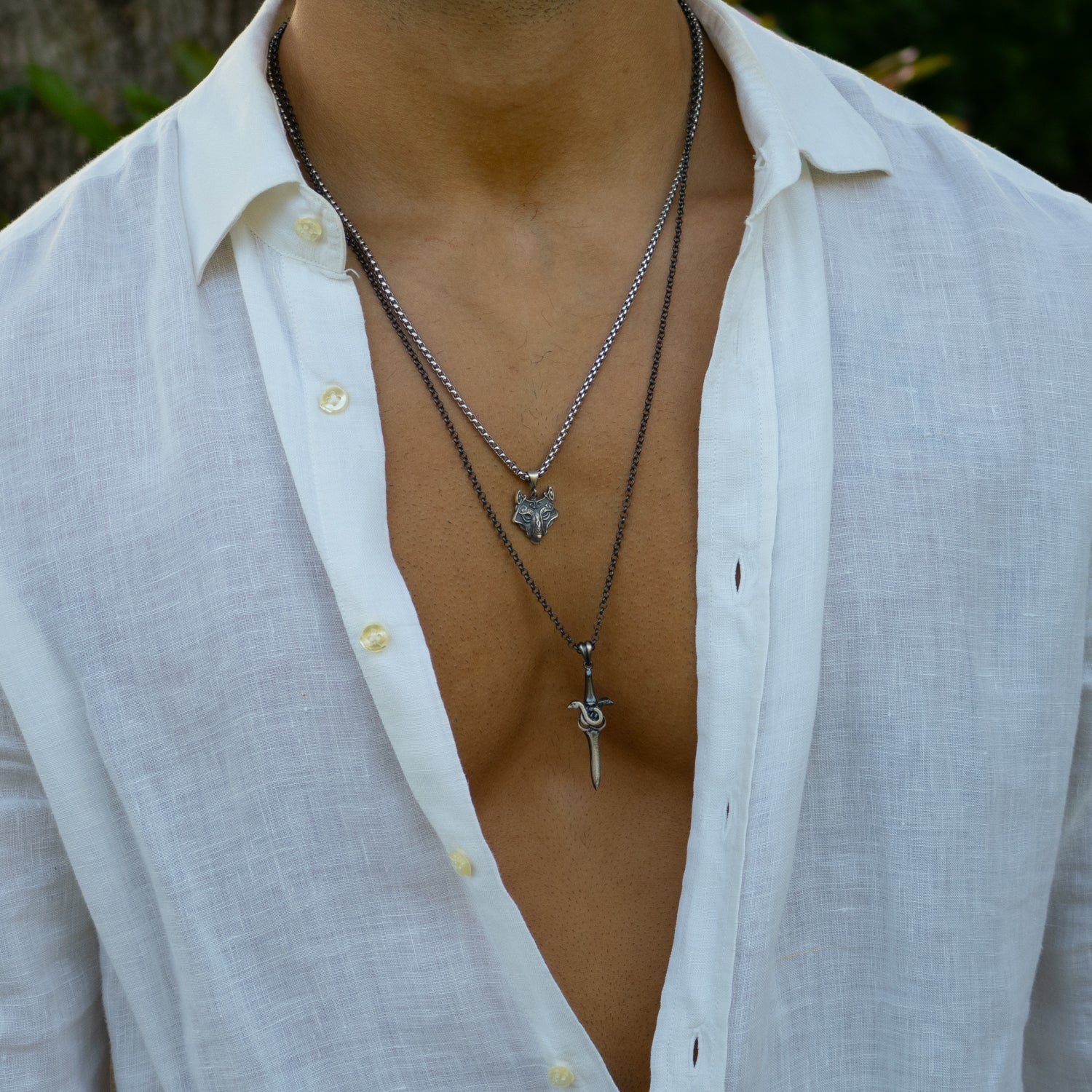 Sterling silver necklace with sword pendant wrapped by serpent, rhodium finish, black and silver accents, bold masculine style.