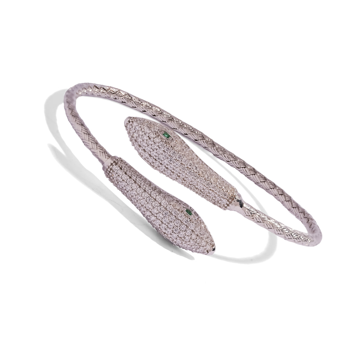 Angled view of the Twin Serpent Emerald Eye cuff showing the emerald green eyes and woven sterling silver band