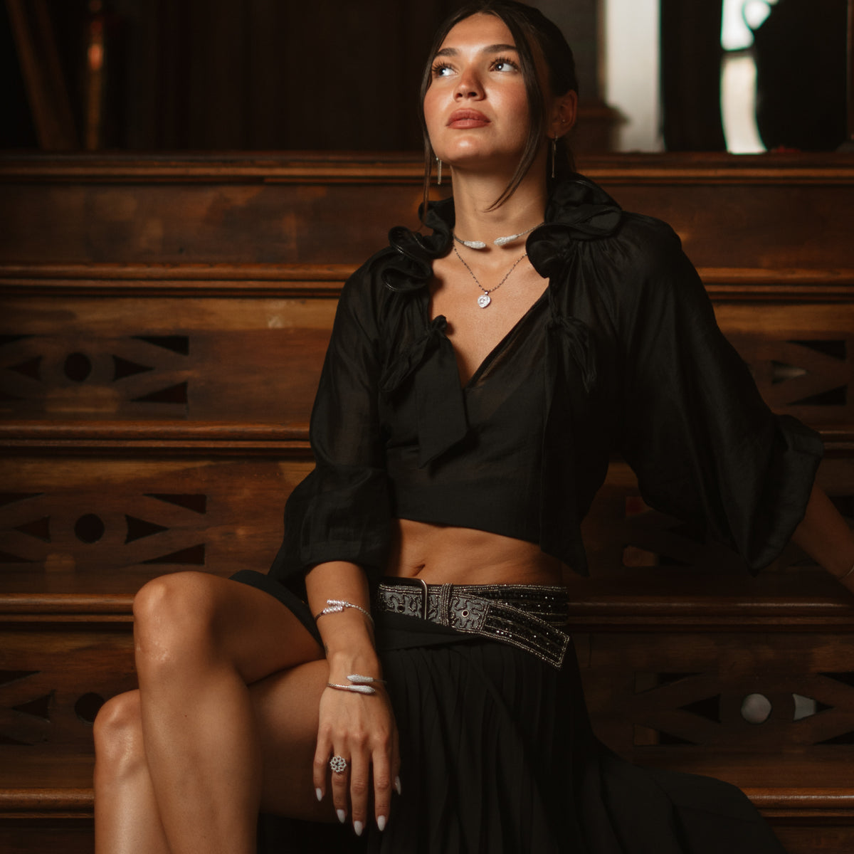 Model in a black crop top and skirt wearing the twin serpent silver cuff on her wrist