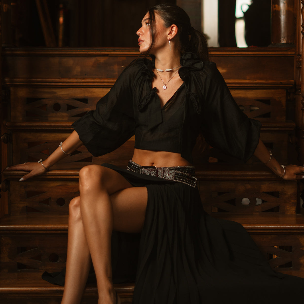 Model seated on a wooden staircase wearing the Serpent Sisters silver collar necklace