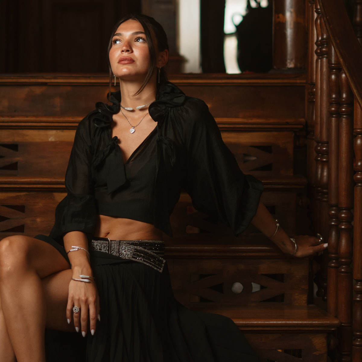 Model on a wooden bench wearing the Serpent Sisters woven silver choker