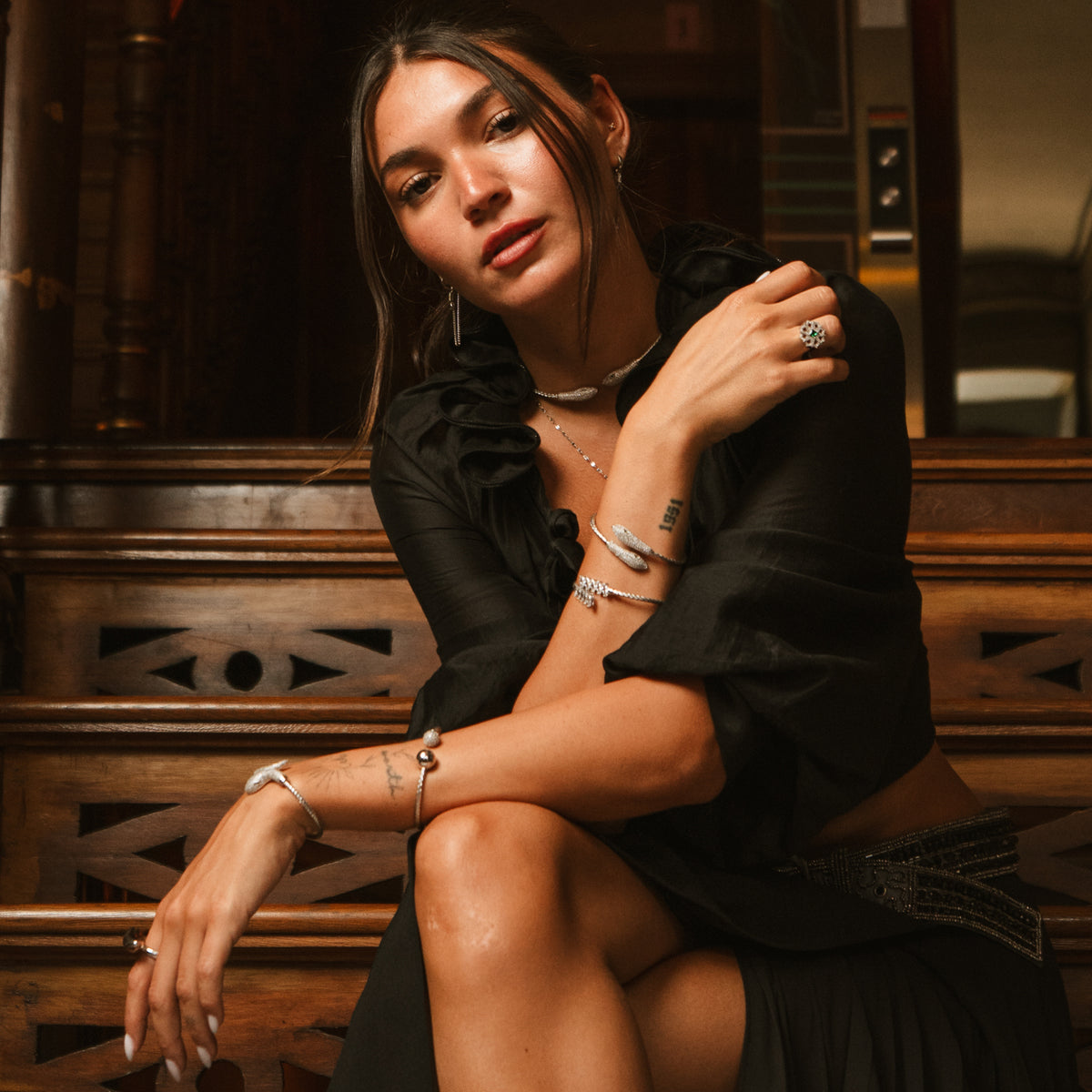 Model on a staircase in black wearing the Serpent Sisters silver choker and stacked bracelets