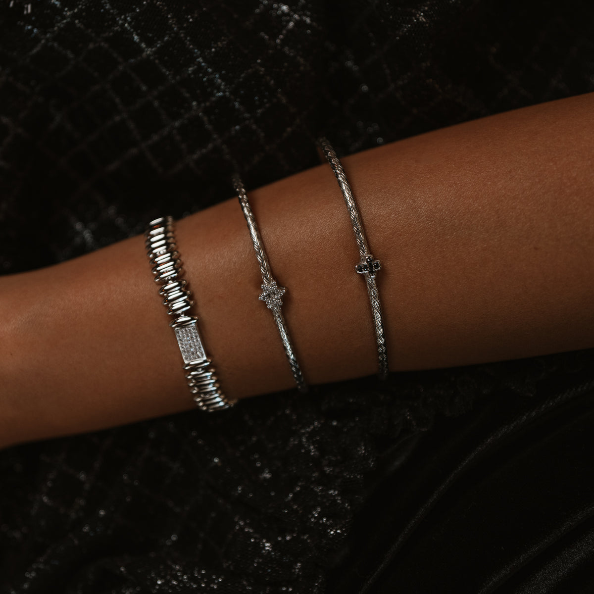 Silver Rhythm Pave Zircon Sculptural Link Bracelet on the forearm beside two slim silver bangles, black sparkle fabric behind