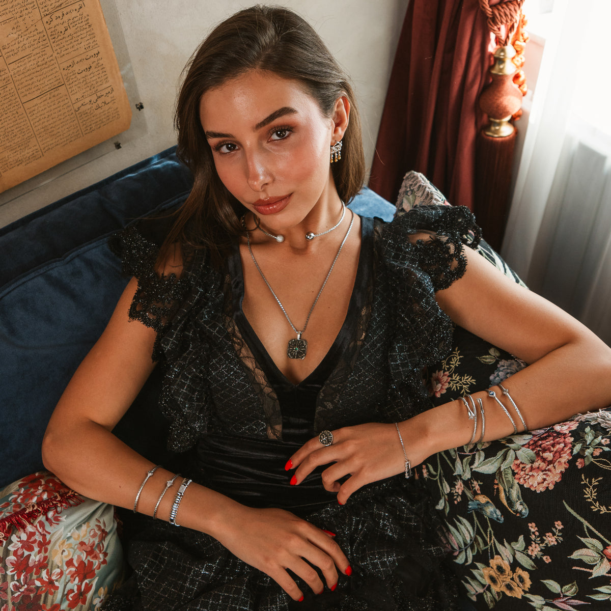 Model in a black lace dress wearing the Silver Rhythm link bracelet stacked with slim silver bangles and layered silver necklaces