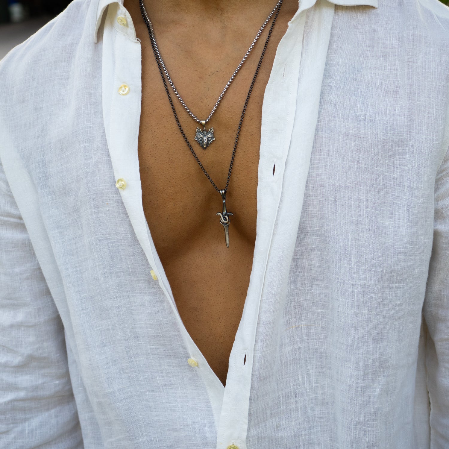 Sterling silver necklace with intricately detailed wolf head pendant, oxidized finish, sturdy silver chain, bold masculine protective style.