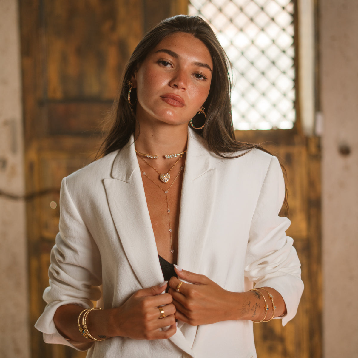 Model in a white blazer wearing a gold big heart statement necklace
