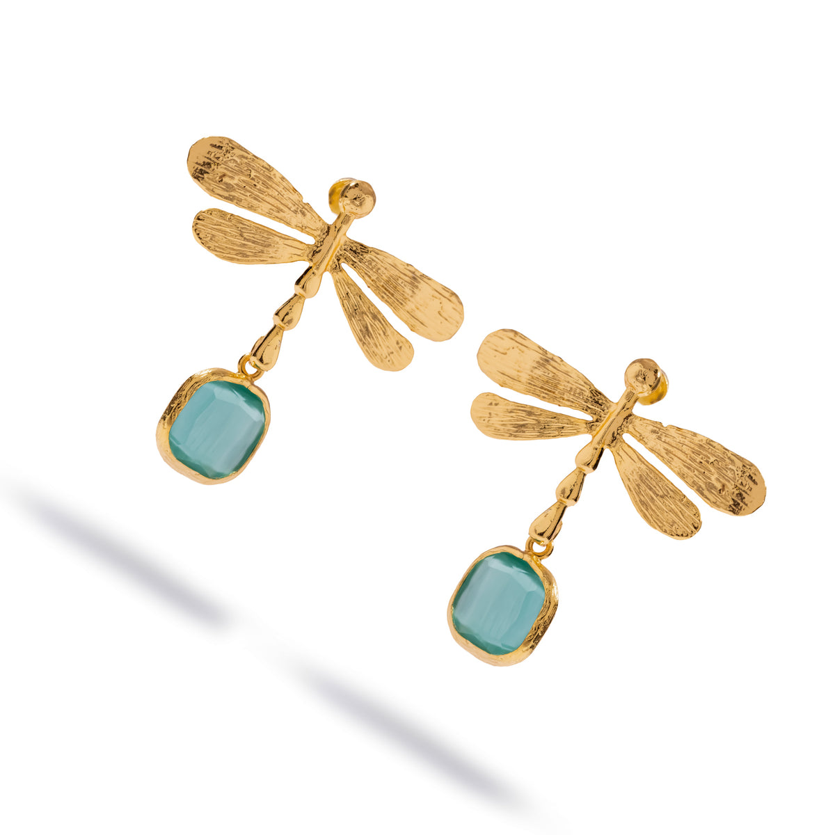 Angled studio view of the gold dragonfly drop earrings showing the textured wings, segmented body and aqua blue stones