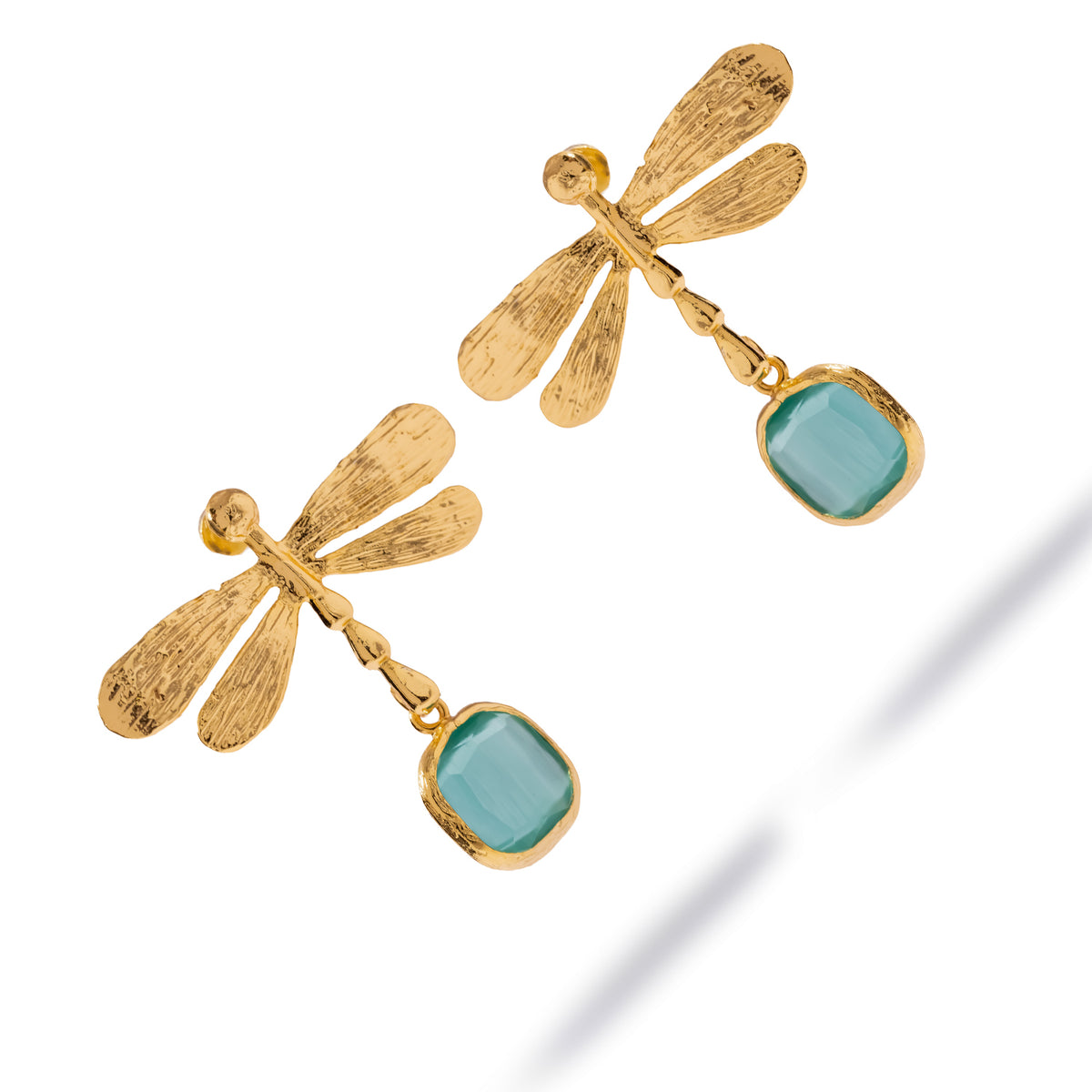Overhead studio view of the Spiritual Dragonfly earrings, the aqua blue cat's eye stones set in textured gold bezels