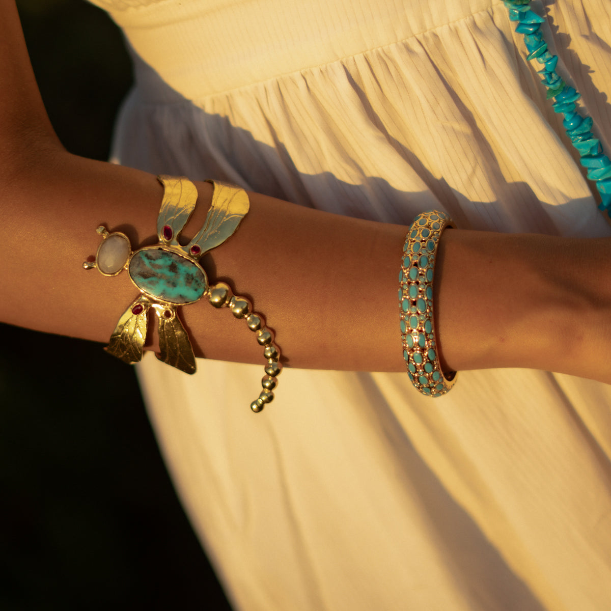 Spiritual Dragonfly Turquoise & Ruby Gold Cuff Bracelet worn on the upper arm in golden evening light