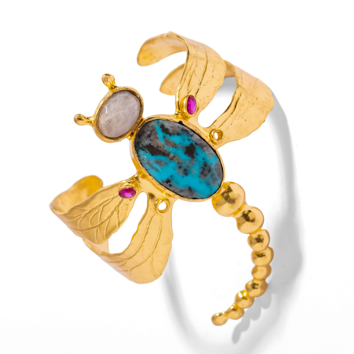 Dragonfly cuff from above, showing the veined turquoise body, moonstone head, ruby wing accents and gold bead tail