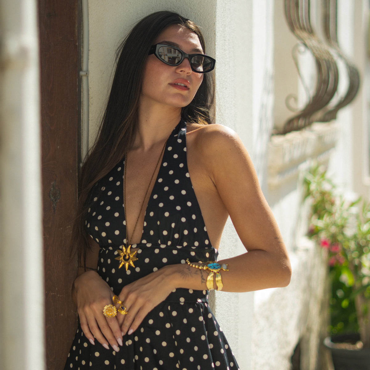 Woman in sunglasses and a polka dot dress wearing the turquoise and ruby gold dragonfly cuff bracelet