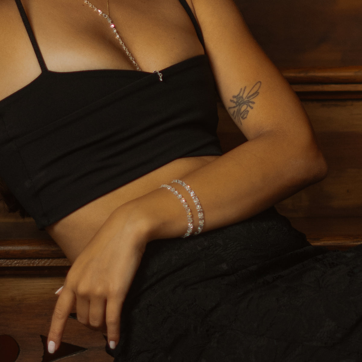 Seated model wearing the Starlight emerald cut and trillion zircon tennis bracelets
