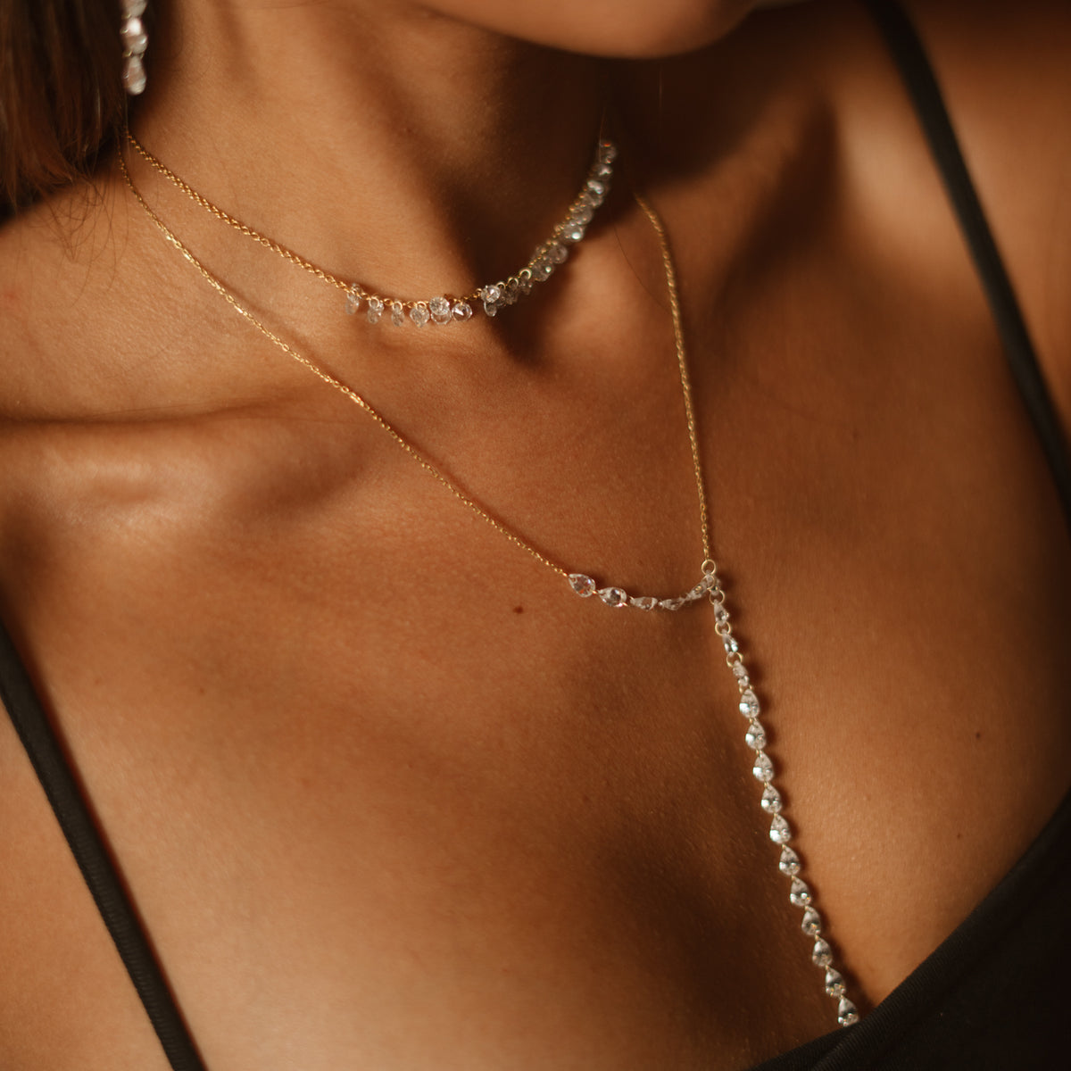 Close up of the Starlight zircon Y necklace on the skin, layered under a zircon choker