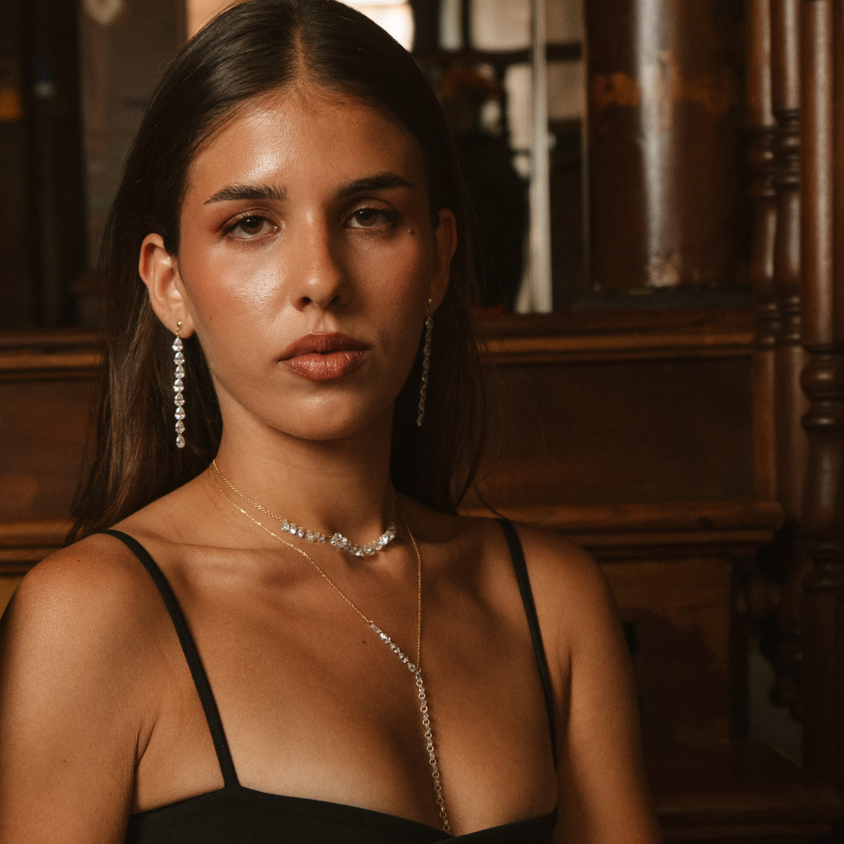 Portrait of the model wearing the Starlight Y drop necklace layered with a zircon choker and drop earrings