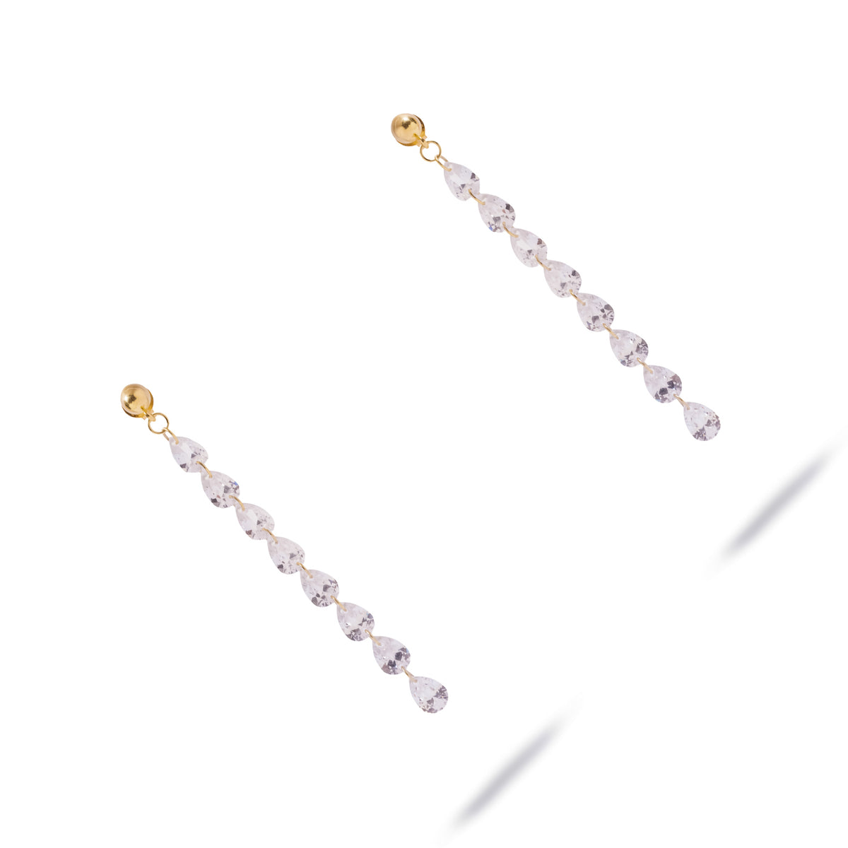 Starlight Pear Cut Zircon Gold Drop Earrings laid diagonally on white