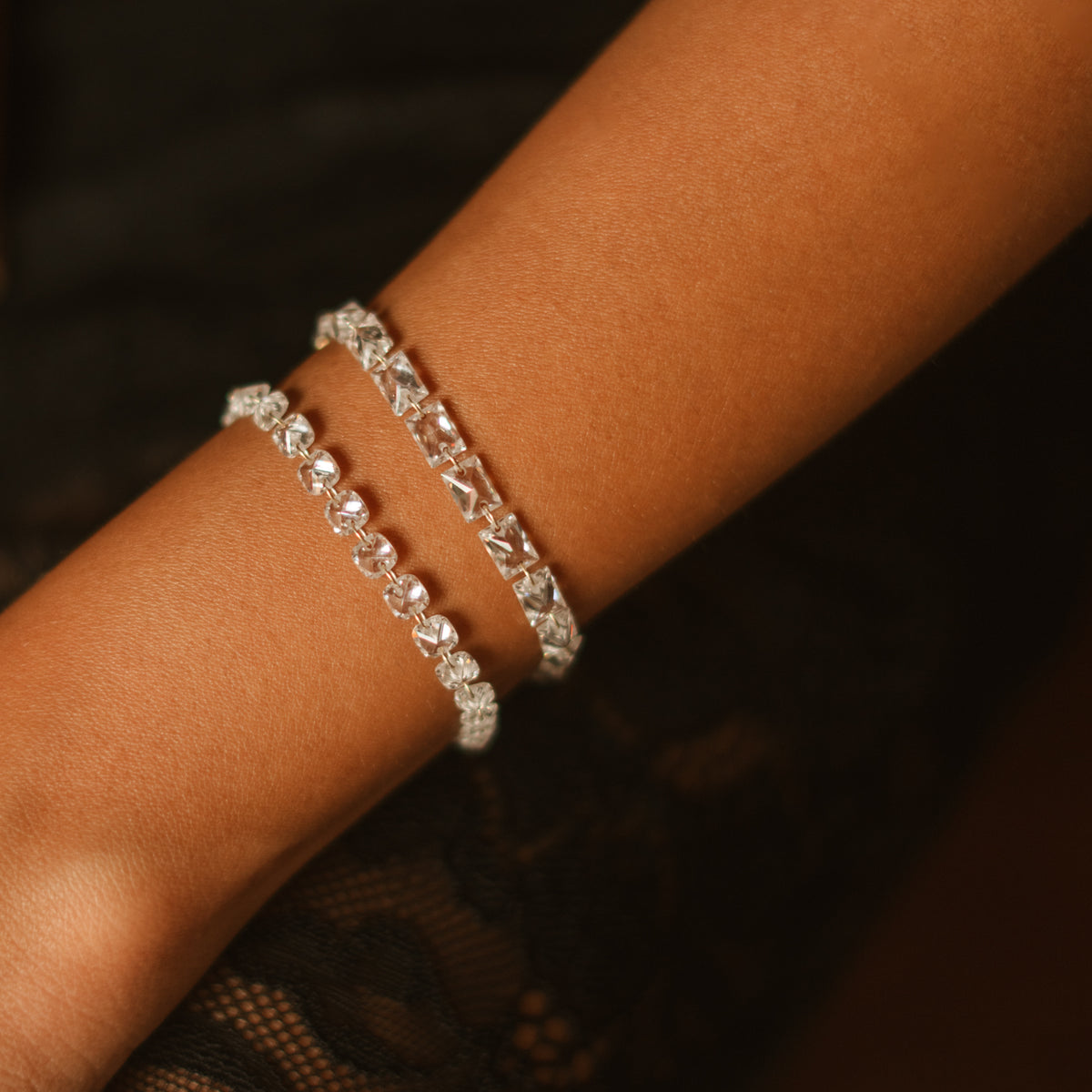 Close up of the Starlight Trillion Cut Zircon Gold Tennis Bracelet stacked with a second zircon bracelet on the wrist