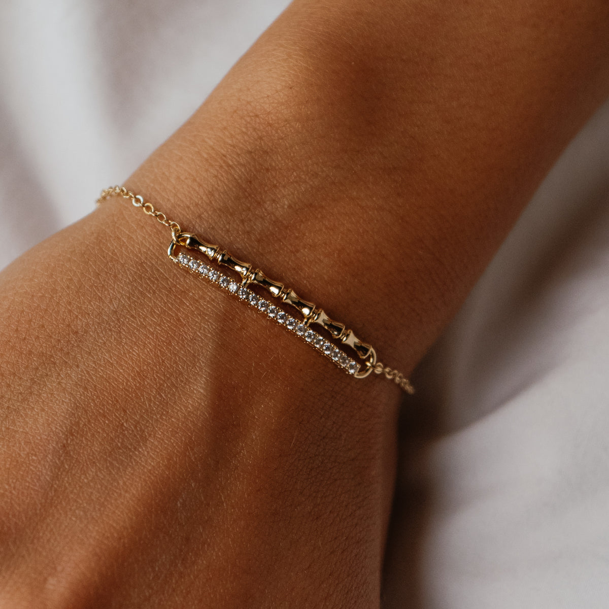 Close view of the Golden Bamboo bracelet on the wrist, six polished bamboo segments over a line of white zircon