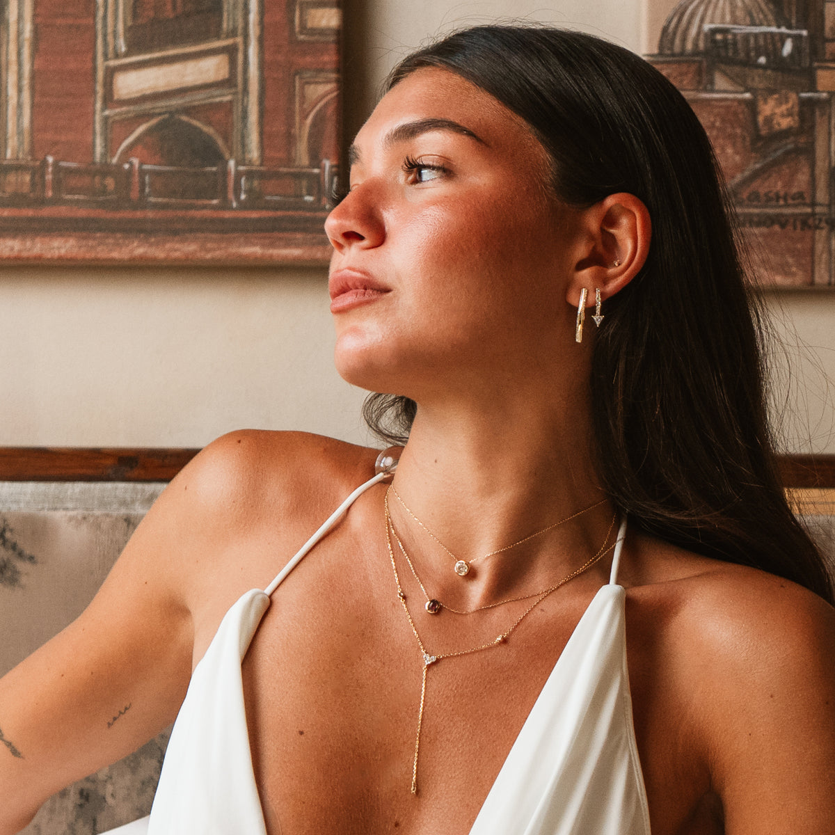 Model in profile wearing the Trillion Arrow Pave Zircon Gold Stud Earrings with fine layered gold necklaces