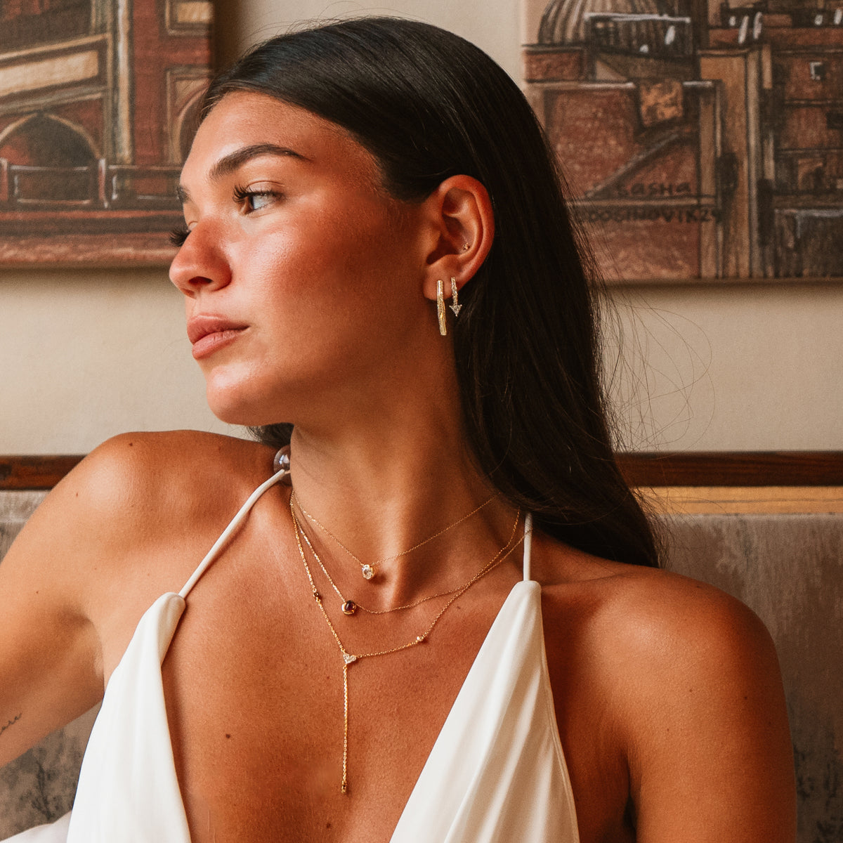 Model in a white halter top wearing the Trillion Arrow Pave Zircon Gold Stud Earring in an ear stack