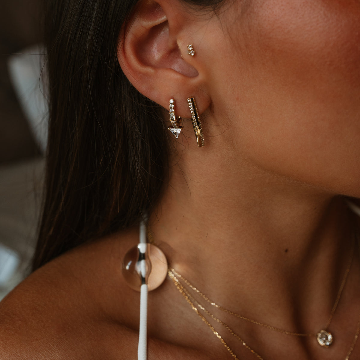 Trillion Arrow gold stud earring stacked with the Twisted Double Row Zircon Gold Hoop Earring and a small upper ear stud