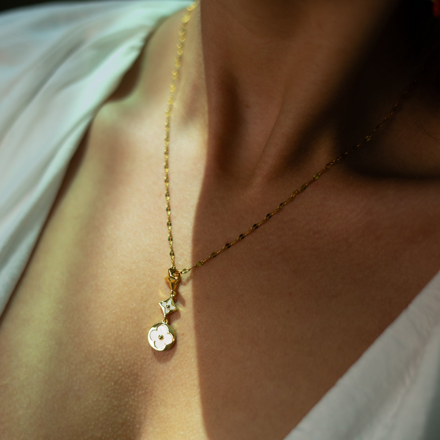 Gold-plated necklace with star, geometric starburst, and flower charms