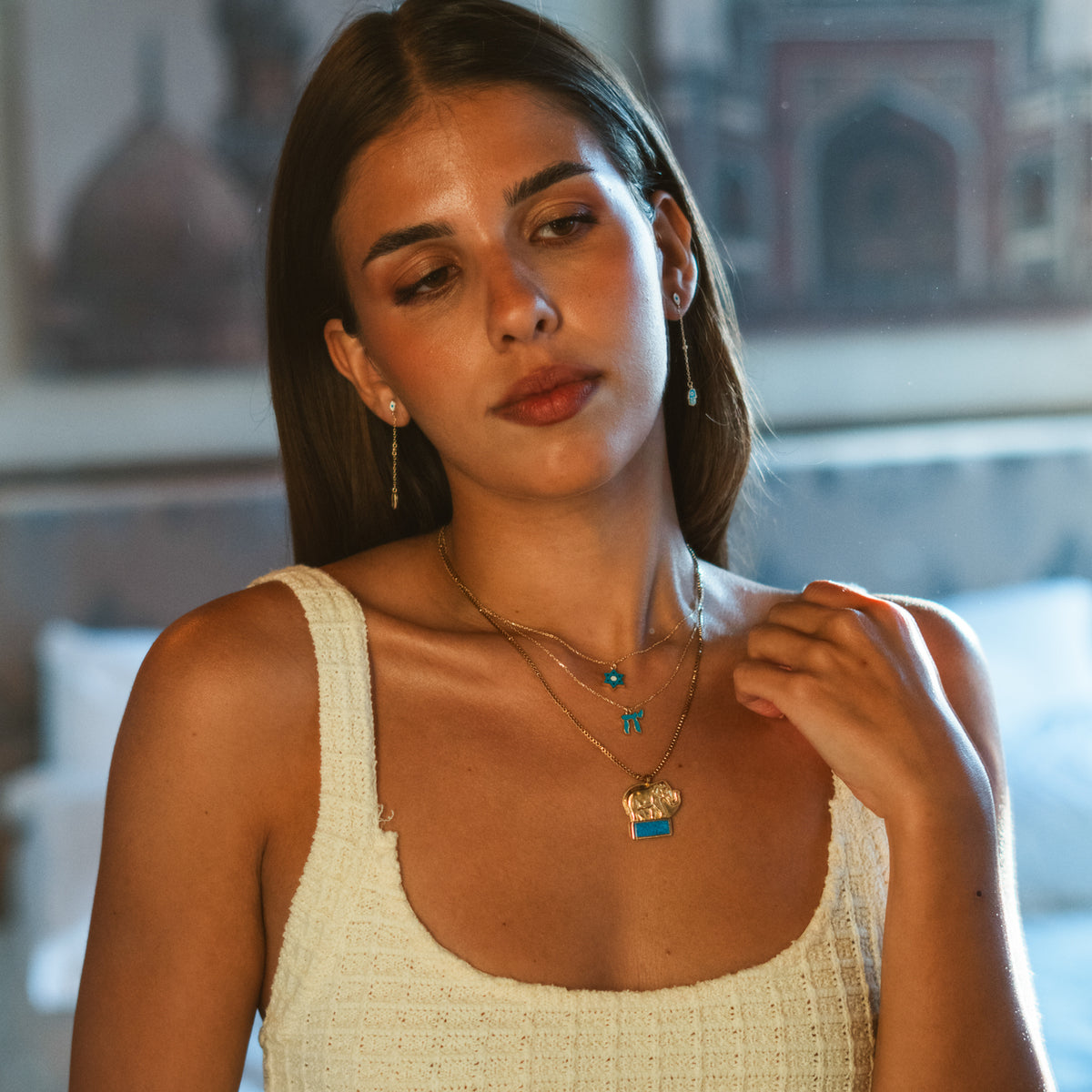 Model in a cream knit top wearing the turquoise Chai gold pendant necklace with layered gold chains