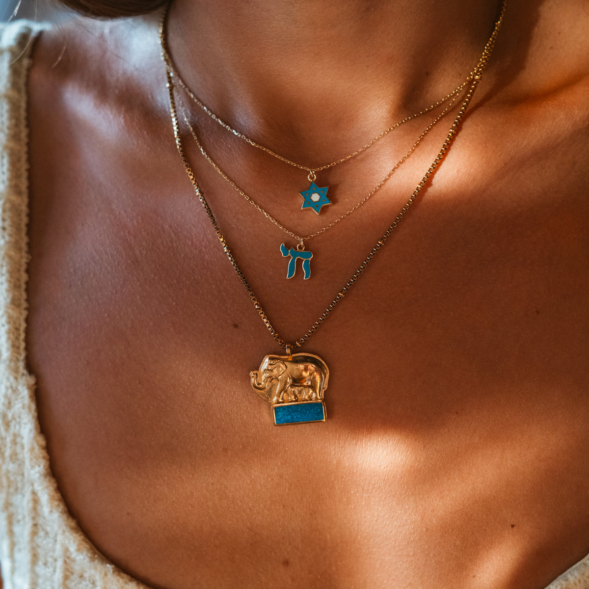 Turquoise Chai pendant layered under a Star of David pendant at the base of the neck
