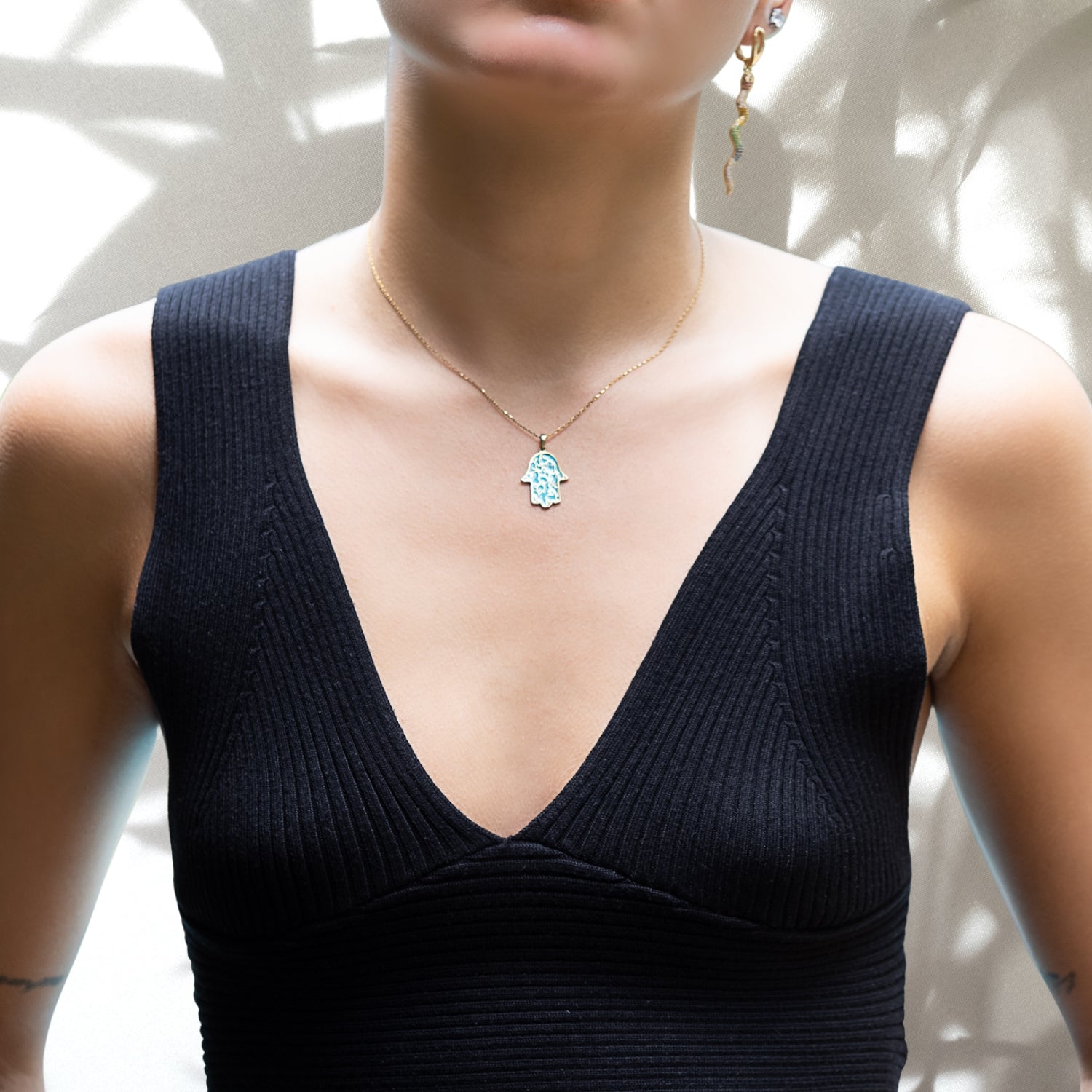 The model radiates positivity while wearing the vibrant Stay Positive Hamsa Necklace, showcasing its hamsa pendant with enamel accents, reminding us to stay positive in all situations.