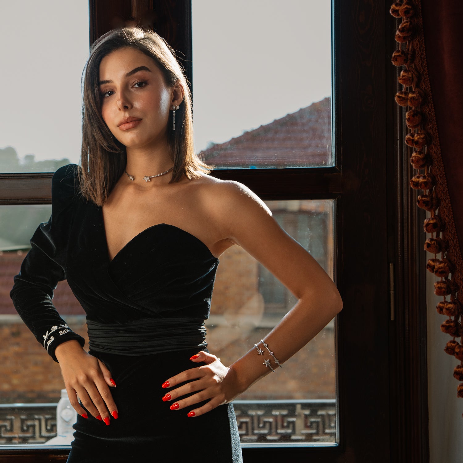 Model by a window wearing a hand woven silver collar necklace with a one shoulder black velvet dress