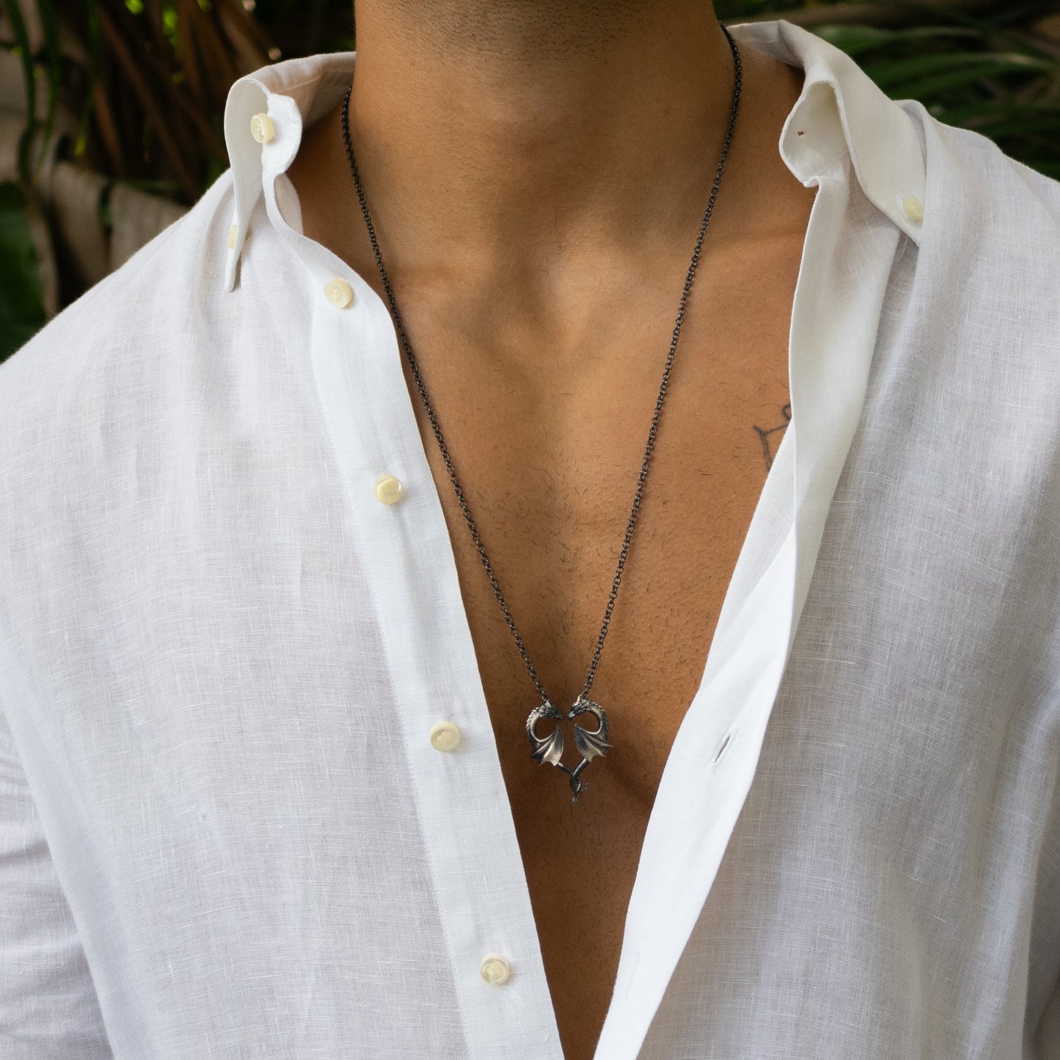 Sterling silver necklace with twin dragons forming a heart pendant, rhodium finish, intricate scales, black accents, bold masculine style.