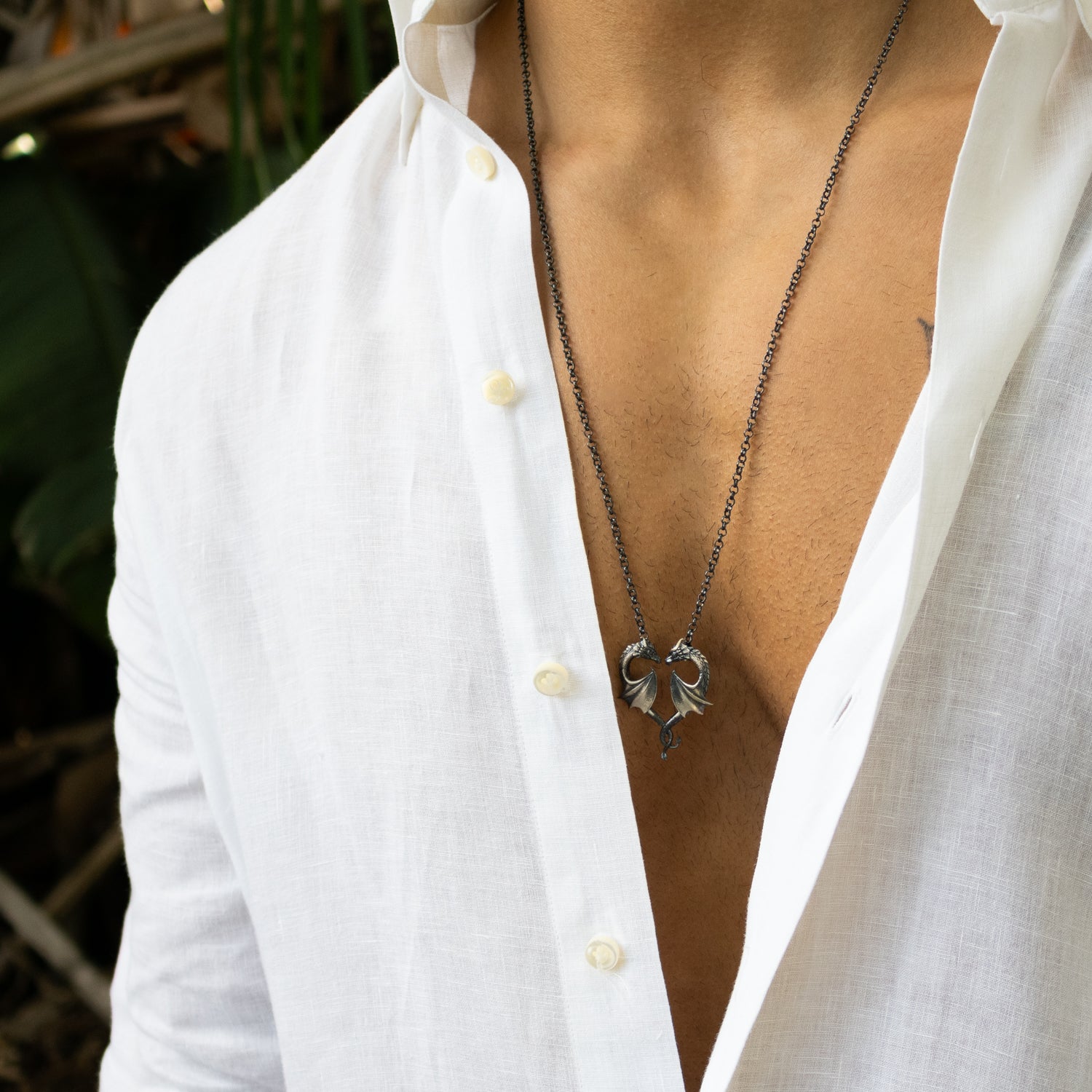 Sterling silver necklace with twin dragons forming a heart pendant, rhodium finish, detailed scales, black accents, strong chain, bold masculine style.