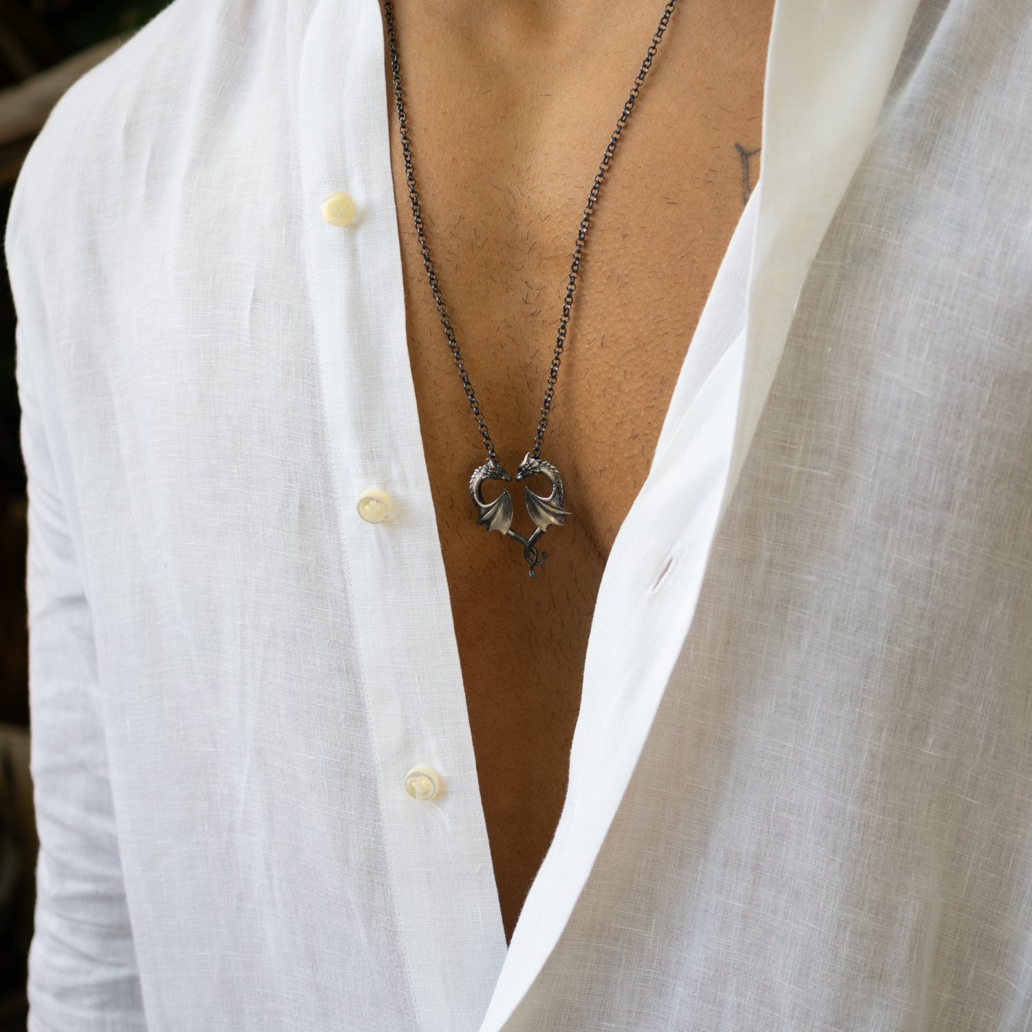 Sterling silver necklace with twin dragons forming a heart pendant, rhodium finish, detailed scales, black accents, bold masculine style.