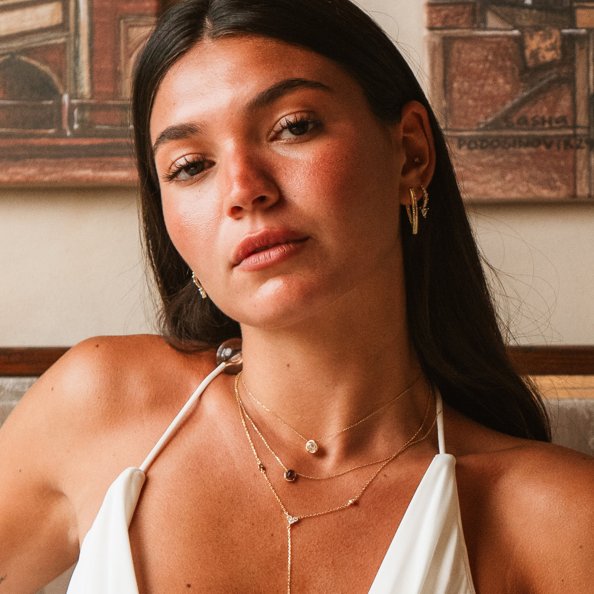 Model looking at the camera wearing the twisted double row zircon gold hoop earrings in a layered ear