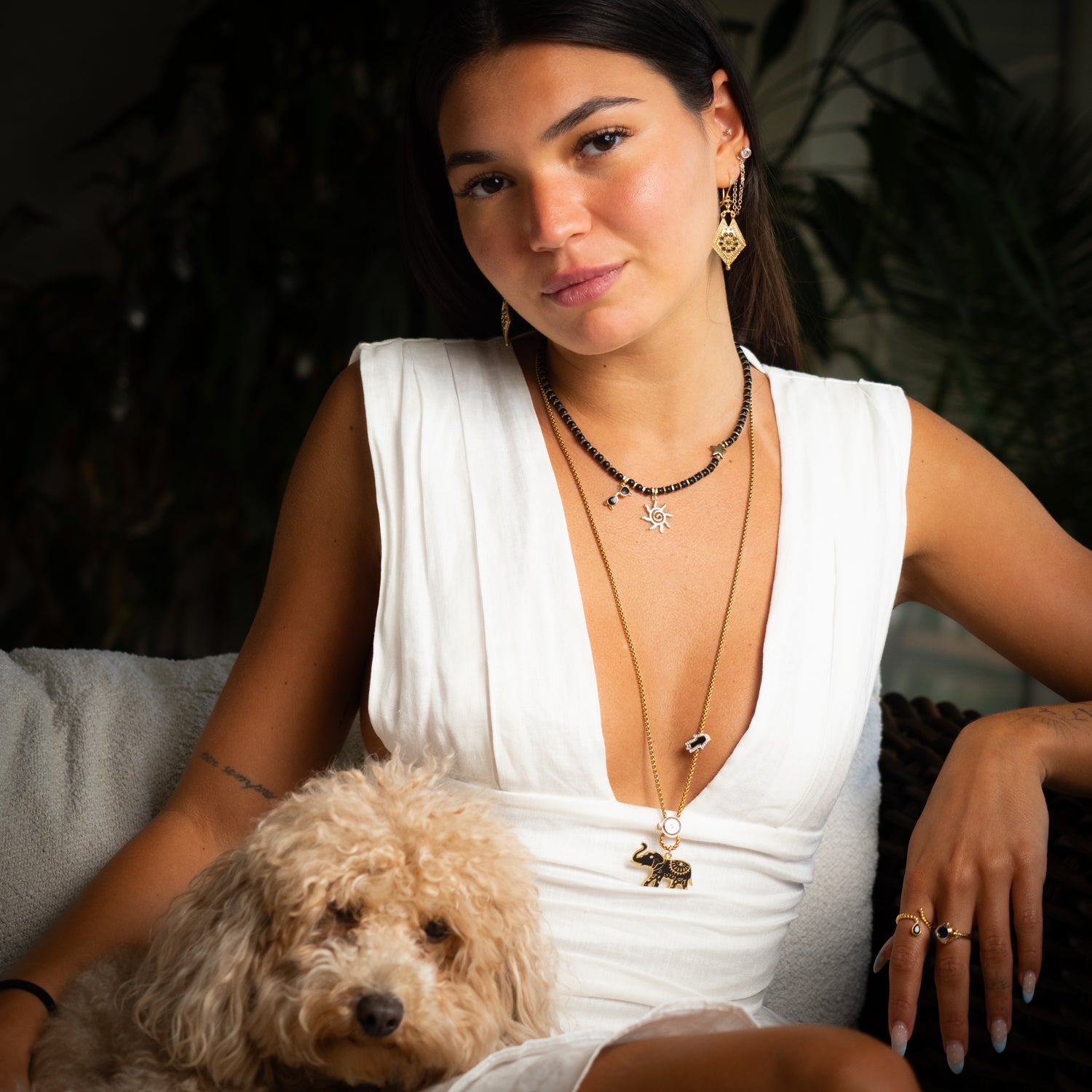Black onyx sun necklace styled with gold layering chain and pendant earrings, summer jewelry look with dog