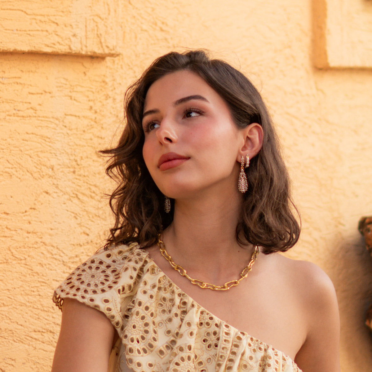 Model in a yellow eyelet dress wearing the vintage zircon teardrop gold earrings with a gold chain necklace