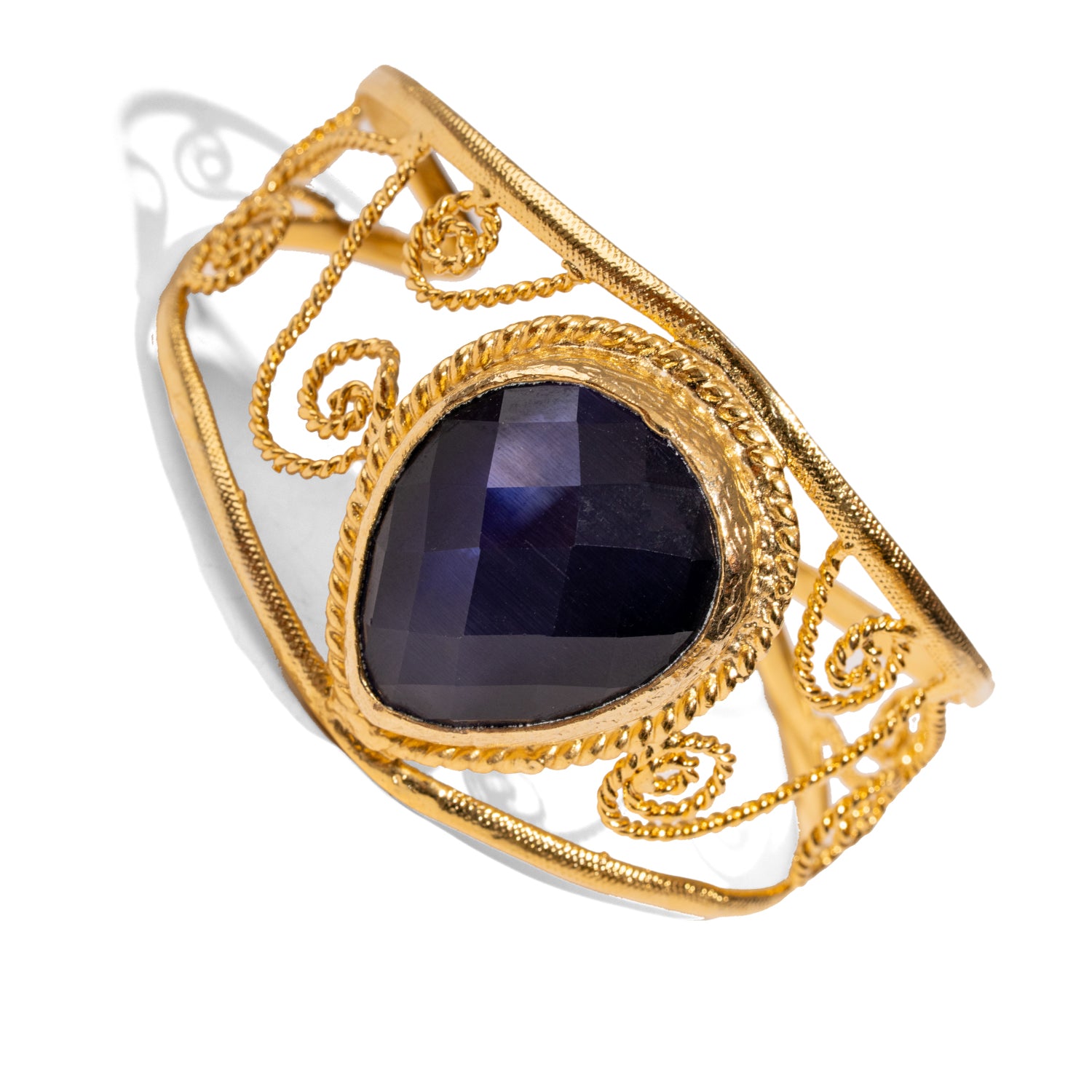 Chunky cuff bracelet in 24k gold-plated bronze with navy blue cat eye stone and ornate gold swirl details, vintage style