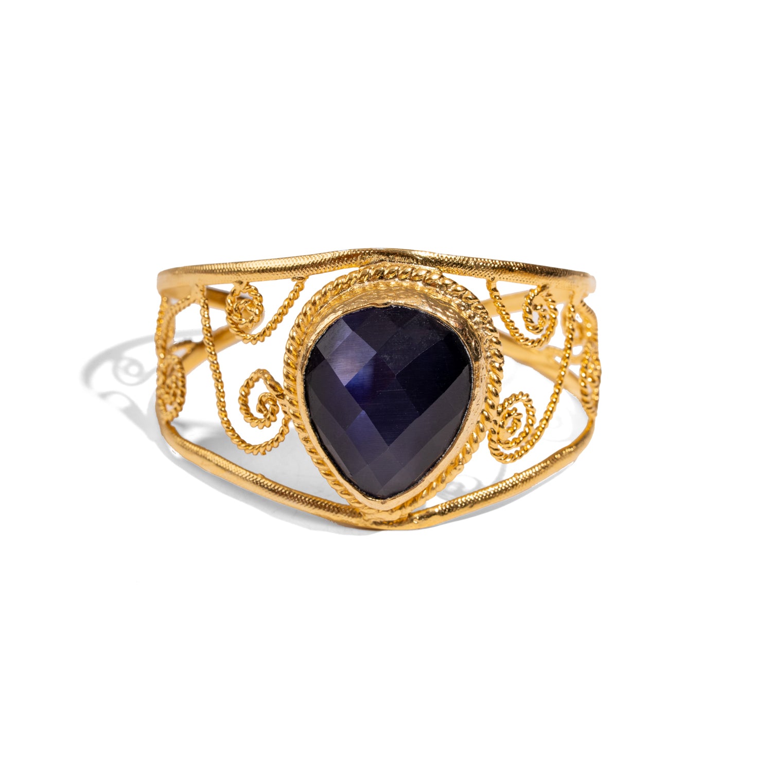 Vintage chunky cuff bracelet in 24k gold-plated bronze featuring a deep navy blue cat eye stone and ornate gold swirl accents