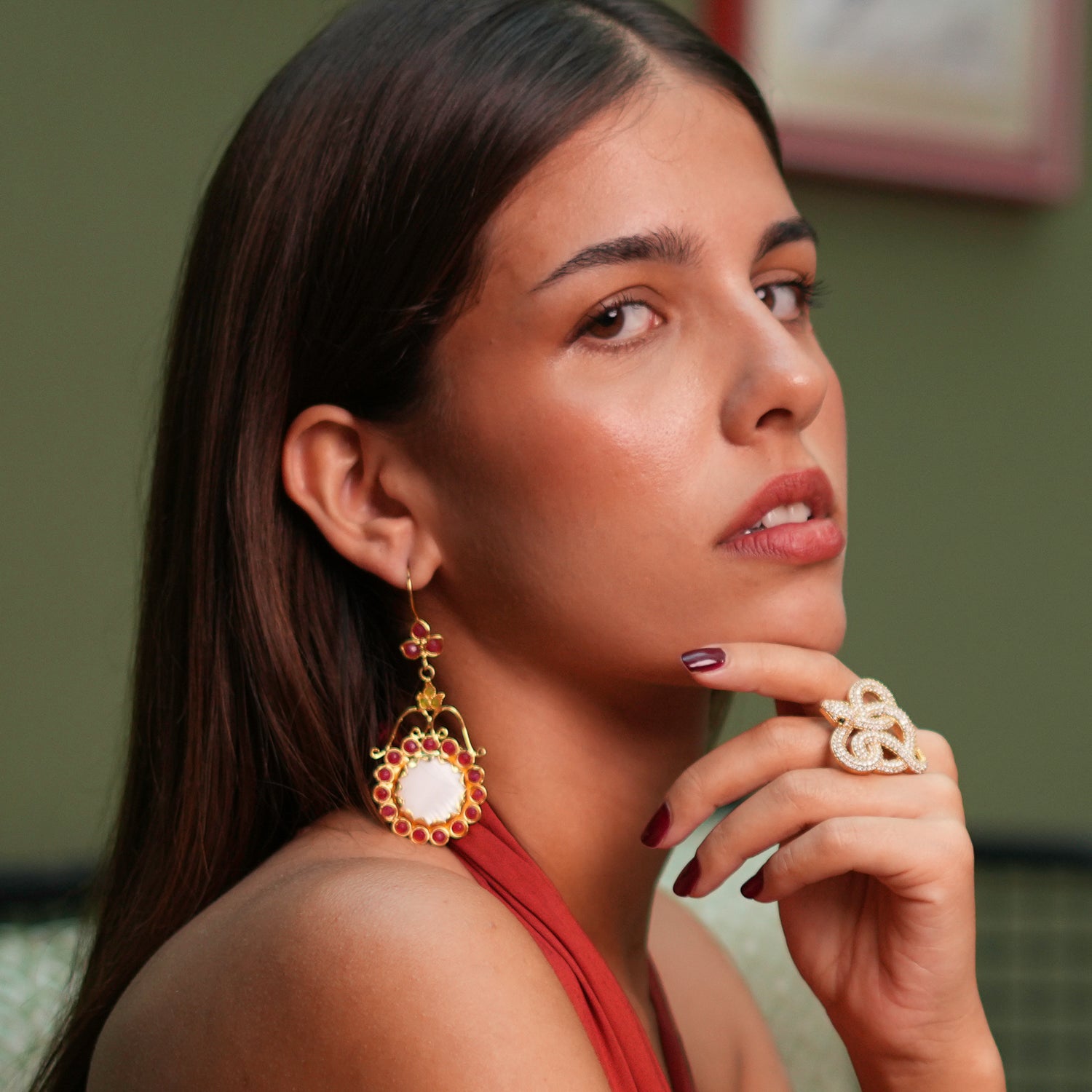 Elegant vintage-inspired gold dangle earrings with a floral motif, adorned with a large mother of pearl stone and accented by ruby and jade gemstones.
