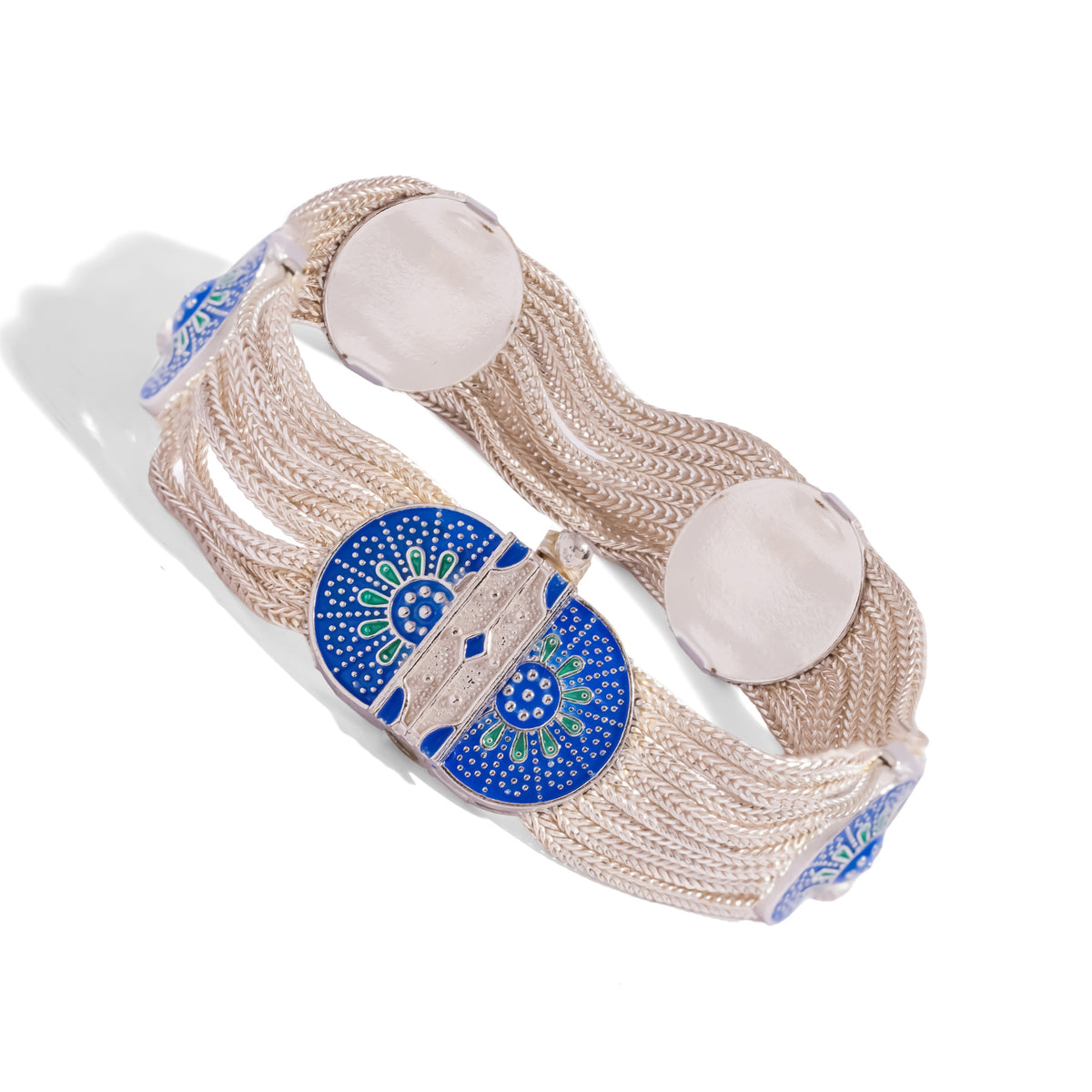 Angled view of the woven silver bracelet showing the enamel medallion clasp and two polished silver discs