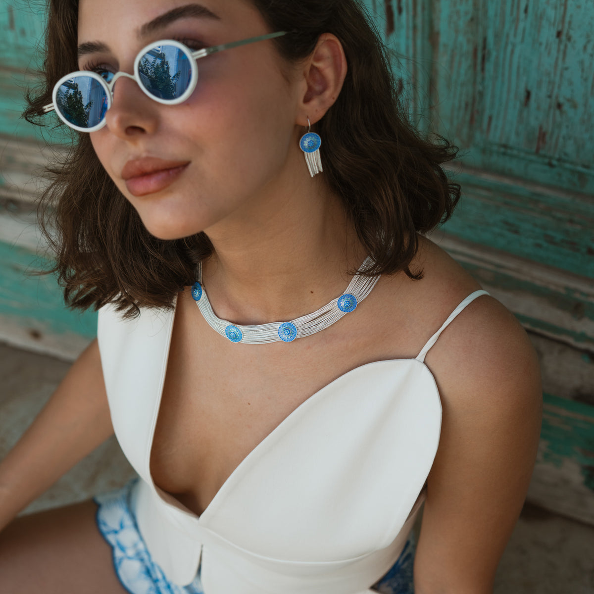 Close view of the cobalt enamel choker at the base of the neck with a matching enamel tassel earring