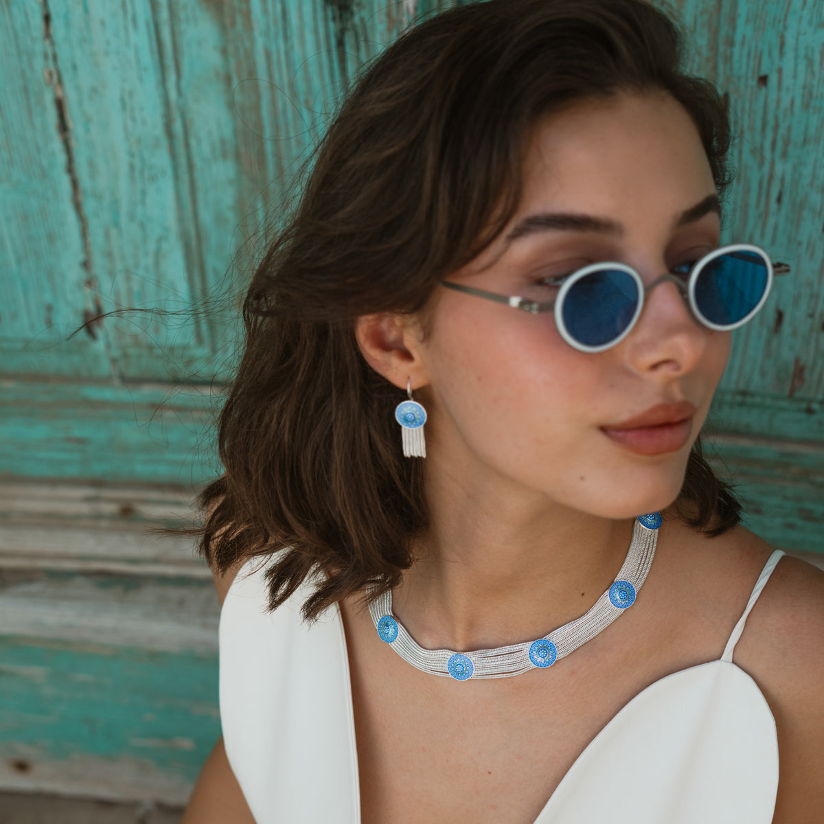 Cobalt Bloom enamel choker and matching tassel earring worn together against a weathered blue door