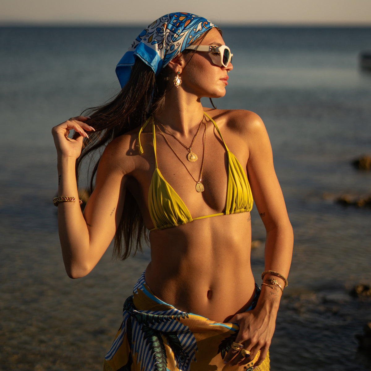 Woman on the beach wearing the Vintage Style Cross &amp; White Zircon Gold Pendant Necklace with layered gold chains