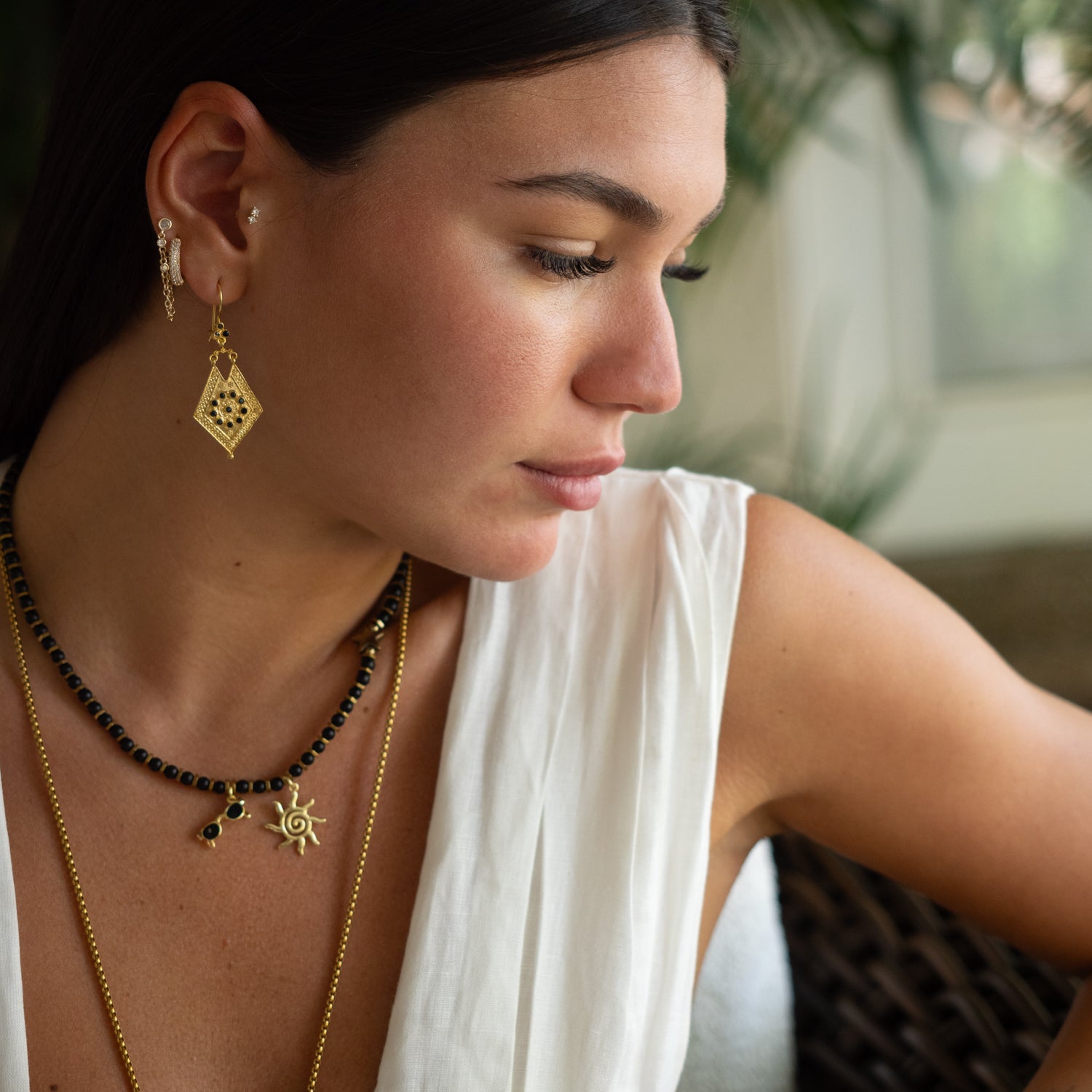 Model wearing Vintage Style Gold & Black Onyx Design Dangle Earrings by Ebru Jewelry, paired with layered gold necklaces and a white linen top.