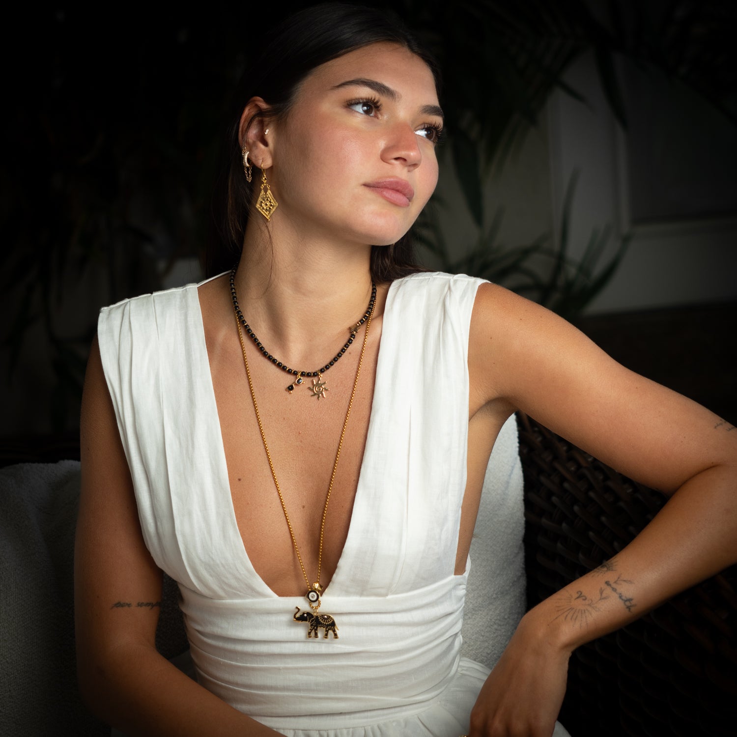Brunette model styled with Vintage Style Gold & Black Onyx Drop Earrings, gold beaded necklaces, and a sleeveless white blouse.