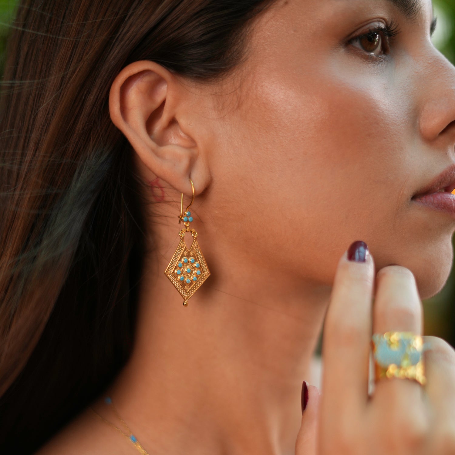 Elegant vintage-style earrings with 24k gold plating, adorned with detailed gold designs and turquoise stones for a captivating look.
